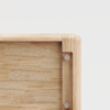 Close-up of the corner of a light wooden box or drawer, showing smooth, rounded edges and visible metal screws securing the joints, against a plain white background.