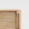 Close-up of the corner of a light wooden box or drawer, showing smooth, rounded edges and visible metal screws securing the joints, against a plain white background.