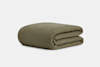 A neatly folded, olive green quilt with a textured, grid-like pattern, set against a plain light gray background.