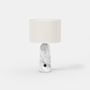 A modern table lamp with a cylindrical white fabric shade and a smooth, white marble base featuring subtle gray veining and a small black circular detail near the bottom, set against a plain white background.