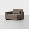A modern, brown upholstered corner chair with a matching rectangular pillow, square armrest on the left, and a minimalist design, placed on a light gray floor with a plain white background.