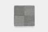 A square swatch of carpet in shades of gray, divided into four smaller squares with slightly different textures and tones, arranged in a 2x2 grid on a white background.