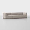 A modern, low-profile beige sofa with square arms and back, three seat sections, and a wooden base, set against a plain white background.