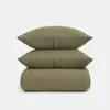 Two olive green, textured pillows are stacked on top of a matching folded blanket, all set against a plain white background.