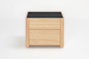 A light wood nightstand with two drawers and a flat, dark-colored top, set against a plain white background.