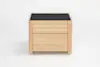 A light wood nightstand with two drawers and a flat, dark-colored top, set against a plain white background.