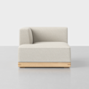 A modern, minimalist corner sofa chair with light beige upholstery and a wooden base, placed on a smooth, light gray floor against a plain white background.