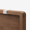 Close-up of a wooden furniture piece with rounded edges, featuring a light gray fabric strap attached to the top edge, set against a plain white background.