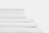 A neatly stacked set of white bed sheets and pillowcases arranged on a white surface, showcasing smooth and crisp fabric.