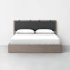 A modern bed with a light wood frame, a dark upholstered headboard, white sheets, and two white pillows, set against a plain white wall on a light gray floor.