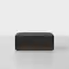 A modern, rectangular ottoman with a dark fabric cushion and a wooden base, placed on a light grey surface against a plain white background.
