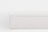 A close-up view of the corner of a white mattress with a soft, textured surface and vertical stitching along the sides, set against a plain white background.