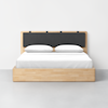 A minimalist wooden bed with a rectangular frame and a black cushioned headboard. The bed is neatly made with white bedding and two pillows, set against a plain white wall on a gray floor.