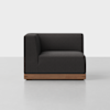 A modern, dark gray corner sofa with clean lines and a wooden base, set against a plain white background and placed on a light gray floor.