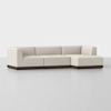 A modern, L-shaped sectional sofa with light beige upholstery and a dark wooden base, set against a plain white background.