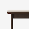 A close-up view of the corner of a wooden bench with a dark brown frame and a light beige cushioned seat, set against a plain white background.