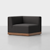 A modern, dark gray corner armchair with clean lines and a low wooden base, set against a plain light background.