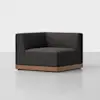 A modern, dark gray corner armchair with clean lines and a low wooden base, set against a plain light background.
