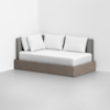 A modern daybed with a wooden base, gray upholstered backrest, and four white pillows, placed in the corner of a minimal, white room.