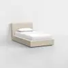 A modern single bed with a beige upholstered frame, white bedding, and a single pillow, set against a plain white background in a minimalistic room.