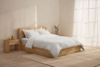 Two fluffy white pillows stacked on top of a neatly folded white duvet, all set against a plain white background.