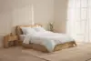 Two fluffy white pillows stacked on top of a neatly folded white duvet, all set against a plain white background.