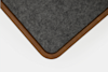 Close-up of a table corner featuring a dark grey felt surface and a rounded wooden edge, set against a plain white background.