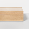 A minimalist, rectangular wooden coffee table with a light natural finish, placed on a light gray floor against a plain white background.