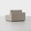 A modern, light beige upholstered armless sectional sofa seat with a low backrest and clean lines, placed on a plain light gray floor against a white background.