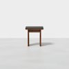 A small wooden stool with a dark cushioned seat, photographed against a plain white background.