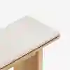 A close-up view of a wooden bench with a light-colored, upholstered cushion, set against a white background.