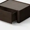 A dark wooden rectangular drawer unit sits on a light gray floor with one drawer partially open, against a plain white background.