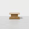 A minimalist, rectangular wooden coffee table with a thick central support and flat base, set against a plain white background.