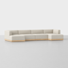 A modern, L-shaped sectional sofa with light beige upholstery and a wooden base, placed in a minimalistic, empty room with a light gray floor and white background.