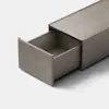 A minimalist, rectangular metallic drawer is partially open, revealing an empty interior. The drawer and its casing are finished in a matte gray color, set against a plain light background.