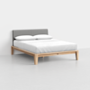 A modern bed with a light wood frame, gray upholstered headboard, and neatly made white bedding with two pillows, set against a plain white background.