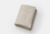 A neatly folded, light beige textured blanket on a white background.