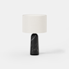 A modern table lamp with a black marble base and a round, off-white fabric lampshade, set against a plain white background.