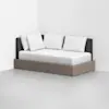 A modern daybed with a wooden frame, dark upholstered backrest, and four white pillows against a white wall in a minimal, light-colored room.
