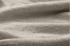 Close-up of a beige, textured fabric with a waffle weave pattern, showing soft folds and a grid-like surface.