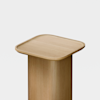 A minimalist wooden side table with a square, slightly rounded top and a solid cylindrical base, photographed against a plain white background.