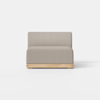 A modern, armless beige upholstered chair with a wooden base sits on a smooth, light gray floor against a plain white background.