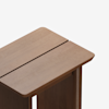 A close-up view of a wooden table with a rectangular top featuring a central groove, smooth edges, and a minimalist design against a plain white background.