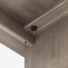 Close-up of the corner of a wooden piece of furniture, showing the joint where two panels meet and a dark screw is fastened into the inner surface.