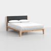 A modern wooden bed frame with a dark gray upholstered headboard, neatly made with white bedding and two white pillows, situated in a minimal, light-colored room.