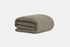 A neatly folded, olive green blanket or comforter is placed on a plain, light gray background.