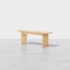 A simple wooden bench with clean lines and a light natural finish, placed on a smooth light-grey floor against a plain white background.