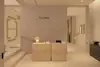 A modern, minimalist store interior with light beige walls and floor, two wooden reception desks, a small lamp, and the brand name THUMA on the wall behind the desks.
