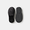 A pair of black slip-on slippers, one showing the fuzzy textured top and the other displaying the patterned rubber sole, set against a plain white background.