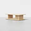 A rectangular wooden coffee table with a minimalist design, featuring an open shelf below the tabletop and a light natural wood finish, placed on a light gray floor against a plain white background.